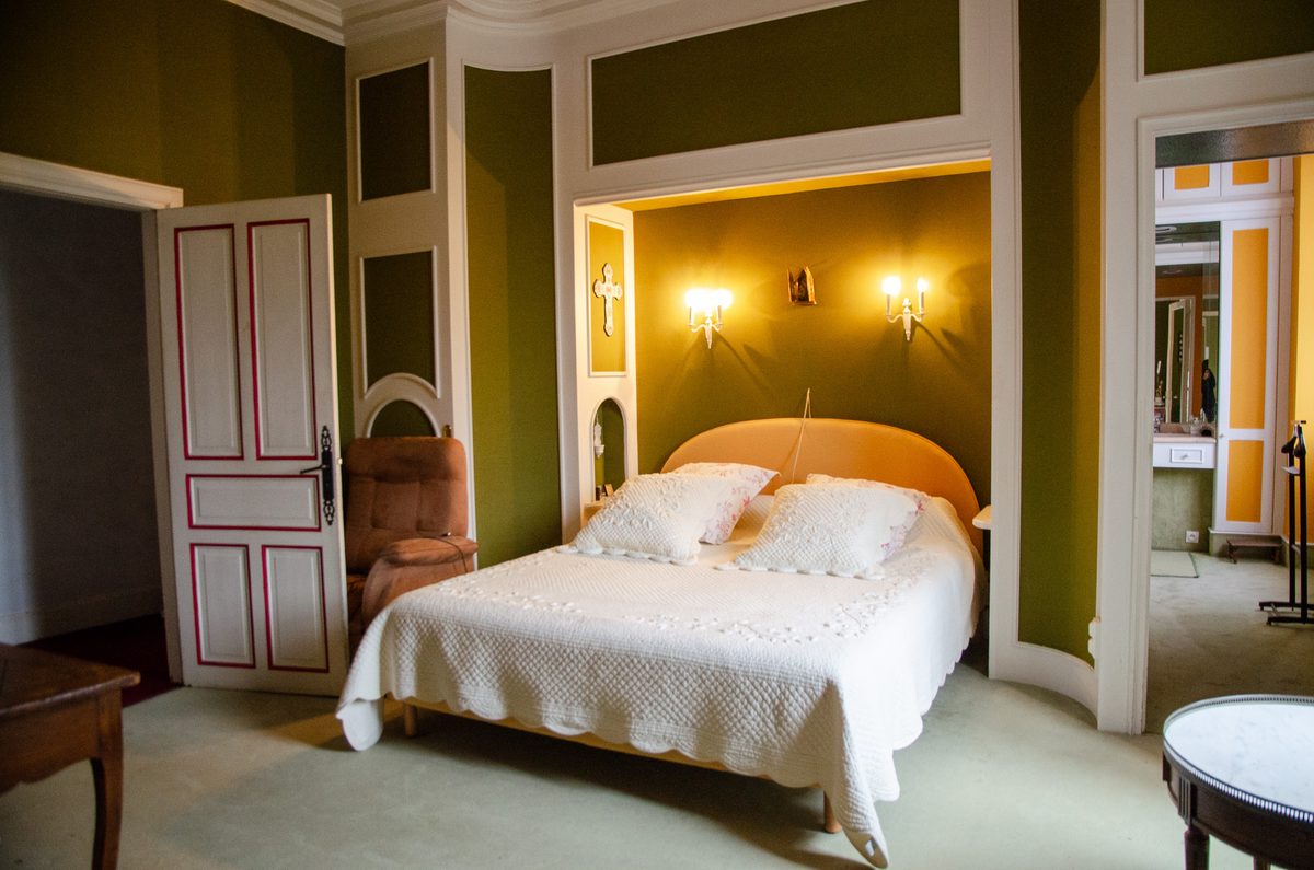 Chambre aux murs verts avec alcôve éclairée et portes à filets rouges